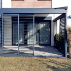 Pergola tkaninowa przyścienna, shuttersy Pergola tkaninowa przyścienna o wymiarach 4,5 × 3 m, Konstrukcja w kolorze antracyt (zbliżony do RAL 7016), Całość uzupełnia zabudowa boczna shuttersy. Materiałowy dach z wodoodpornej tkaniny DRIPLUX – szary na zewnątrz i jaśniejszy od środka, Dach jest sterowany elektrycznie systemem SOMFY. Spin Szczecin