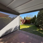 Pergola tkaninowa przyścienna, rolety boczne Helio Zip Screen Pergola tkaninowa przyścienna 4 × 3 m z rozsuwanym dachem z tkaniny Opatex. Po bokach rolety Helio Zip Screen oraz boczne trójkąty z tkaniny. Całość wyposażona w silniki Somfy io, Spin Szczecin